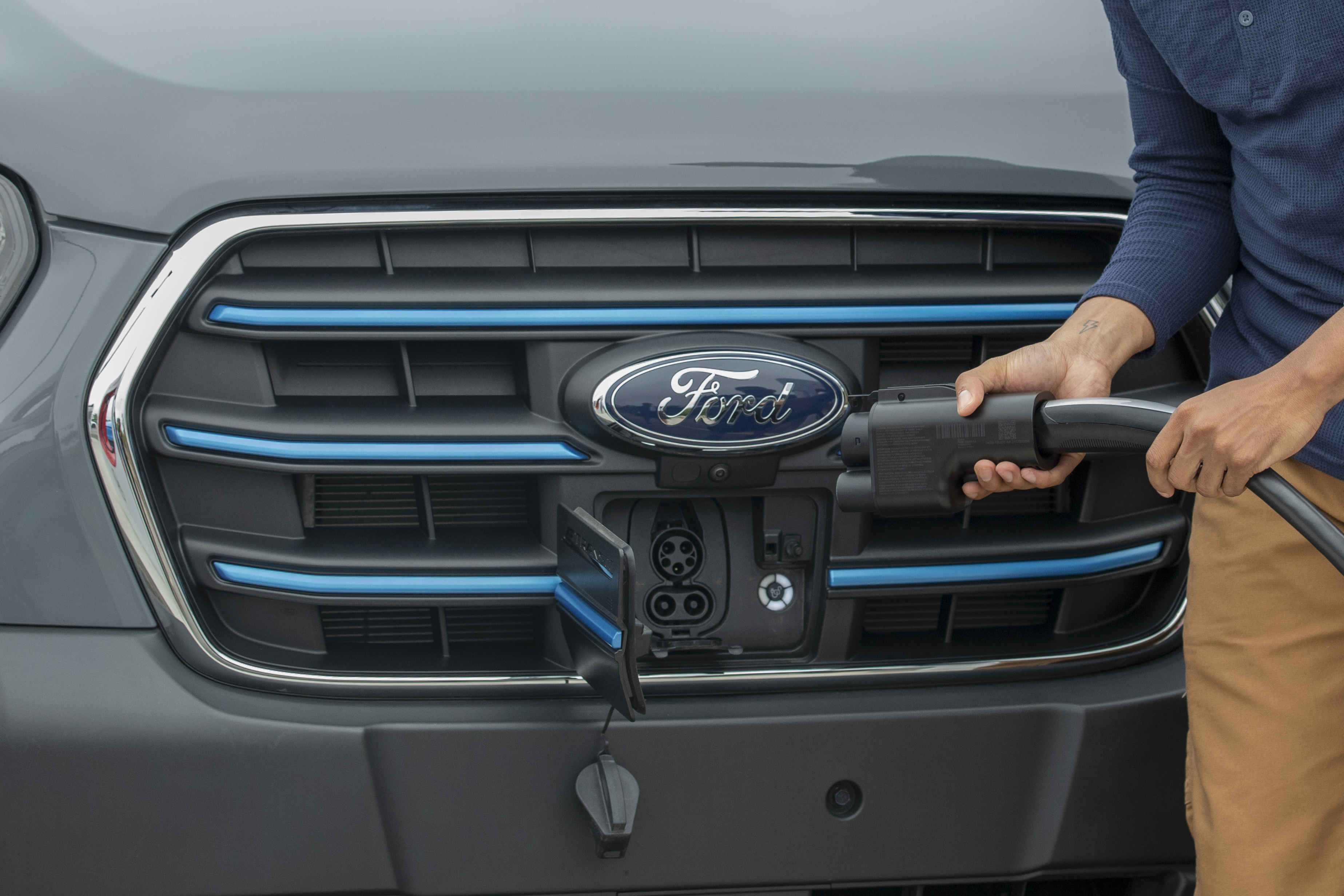 A charger adapter is shown near the charging port of a Ford electric vehicle.